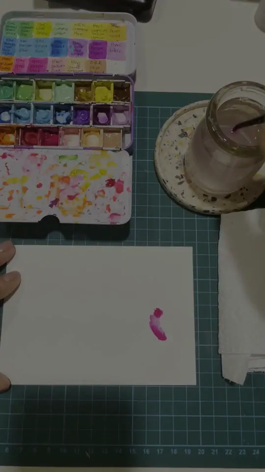 Overhead view of a brush laying a magenta stroke onto a white card