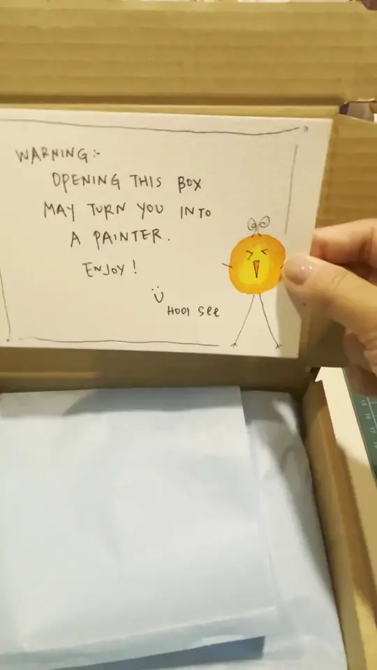 A hand-lettered note reading opening this box may turn you into a painter, being tucked into a kit box