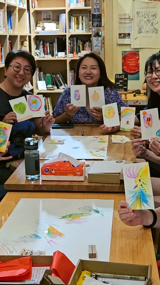 Four people holding up the watercolour birds they just painted, all smiling