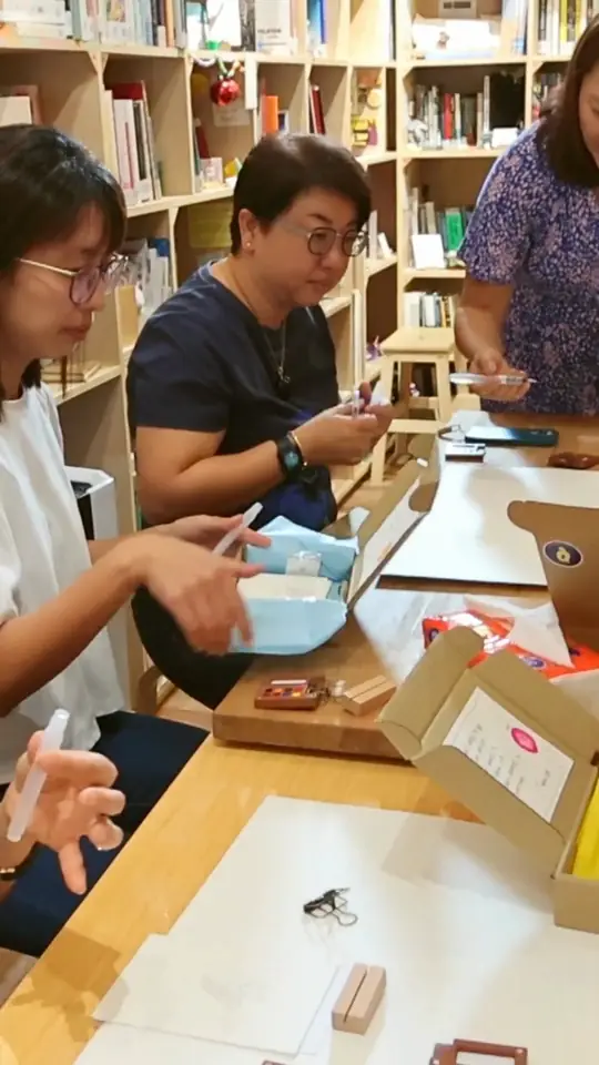 Hands opening the kraft paper workshop kits at the table