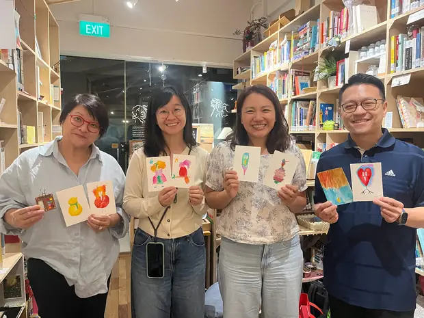 Four people standing side by side, each holding the bird they painted