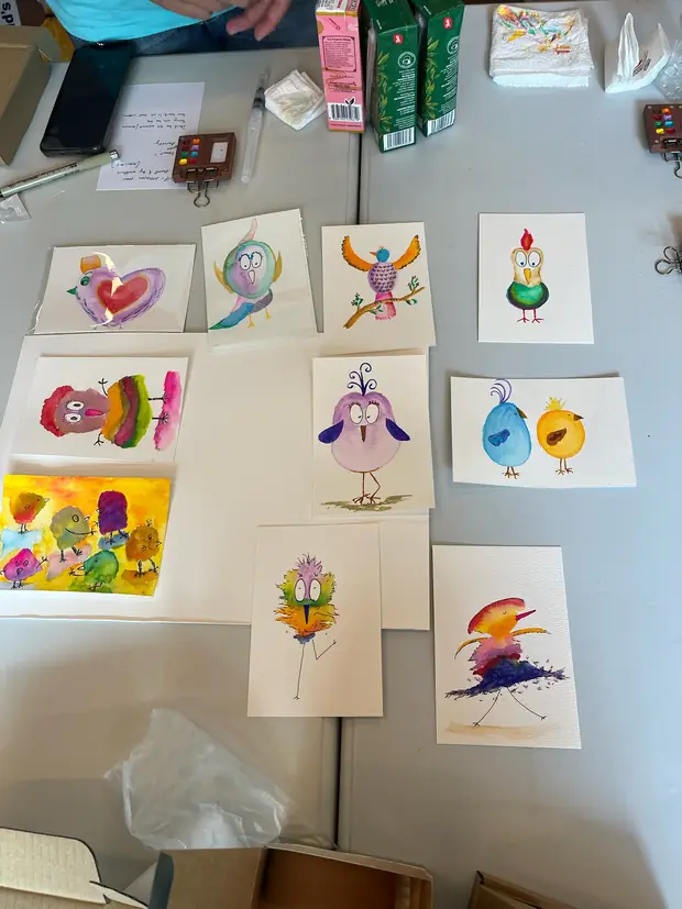 Ten finished watercolour birds spread across a white table