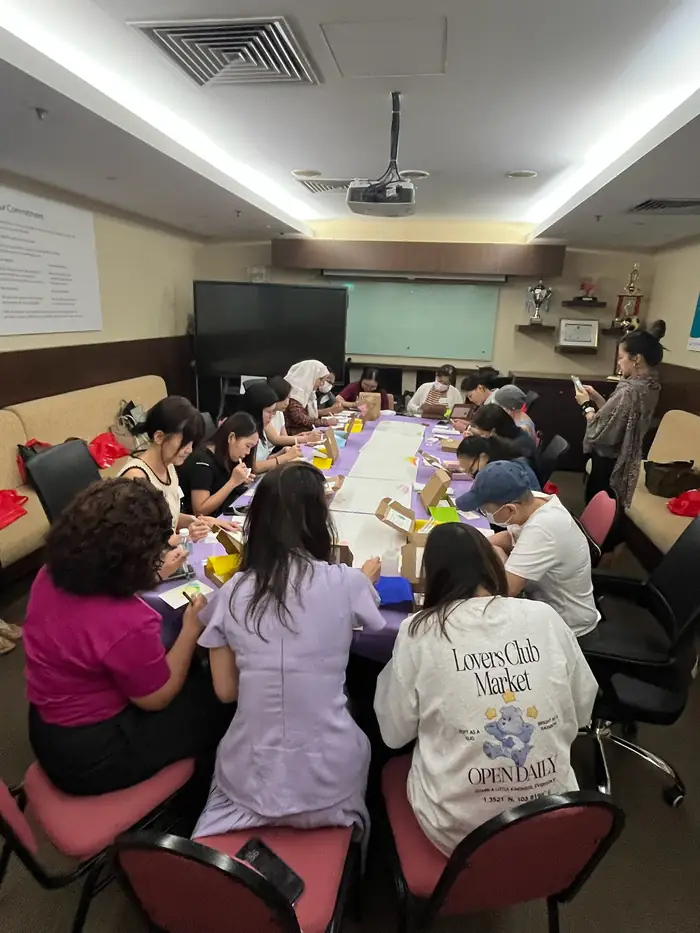 A boardroom with people painting at long tables pushed together